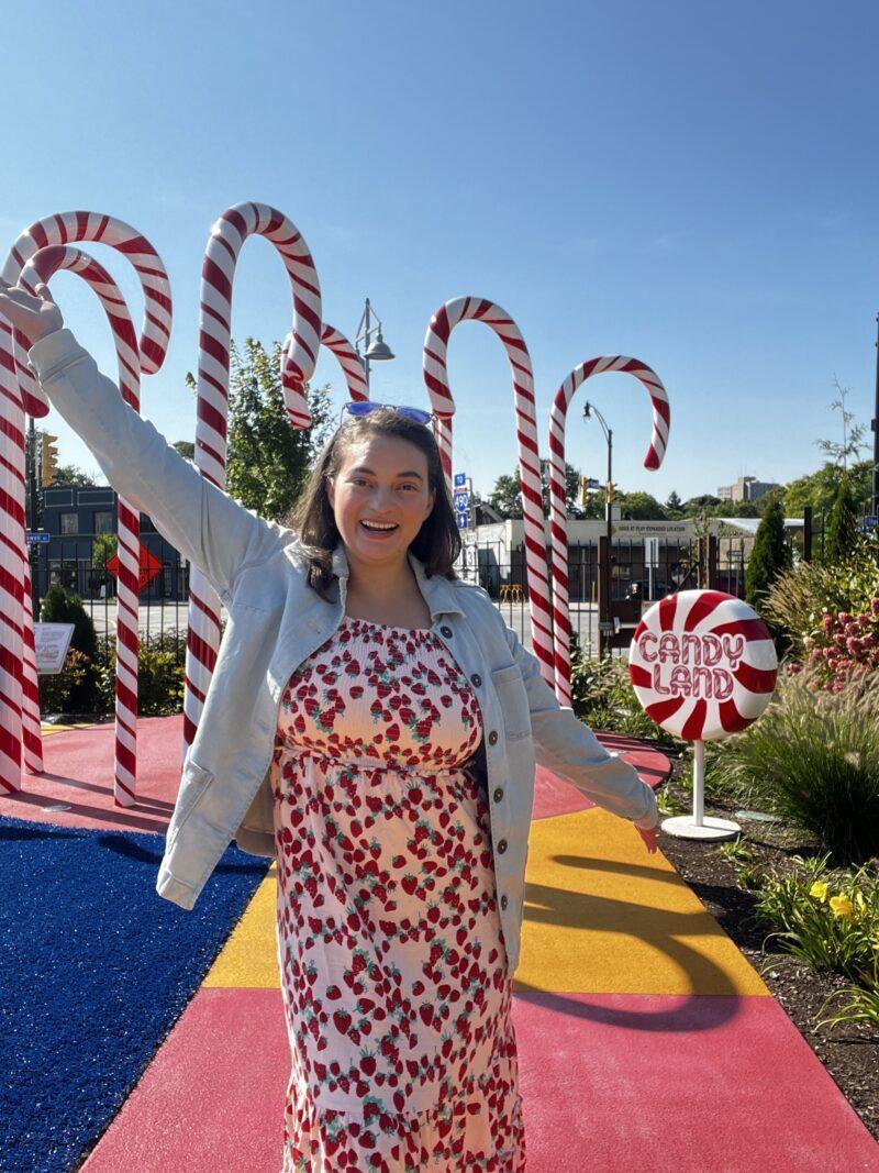 Woman with hands outstretched in front of giant candy canes