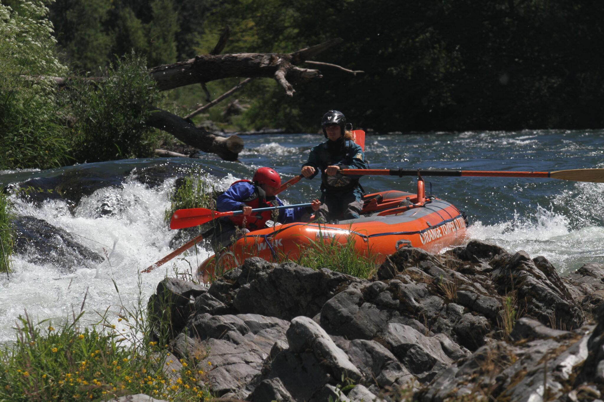 Man and woman on orange raft in rapids