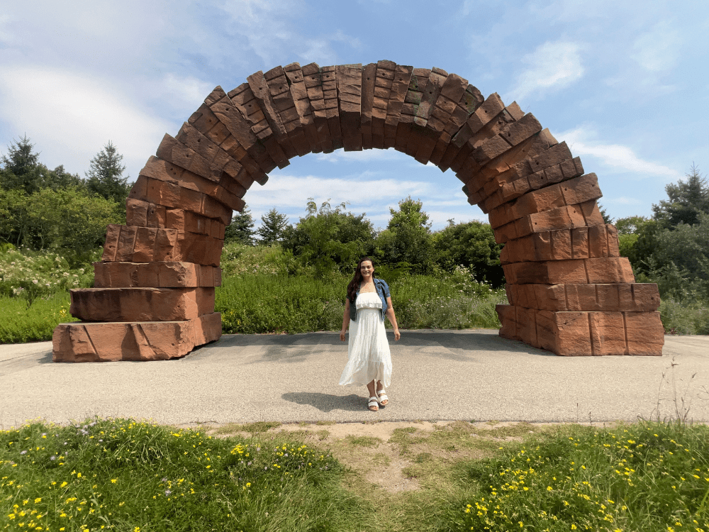Woman standing underneath rock arch sculpture